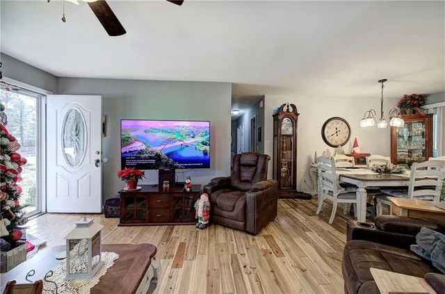a living room with furniture kitchen view and a wooden floor