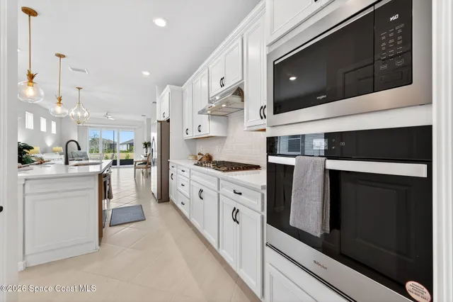 a kitchen with stainless steel appliances granite countertop a sink a stove and white cabinets