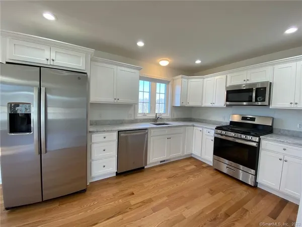 a kitchen with granite countertop a refrigerator stove and microwave