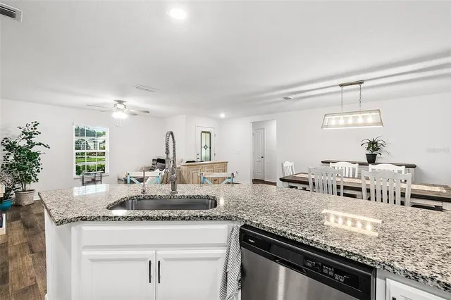 a kitchen with granite countertop a sink and white cabinets