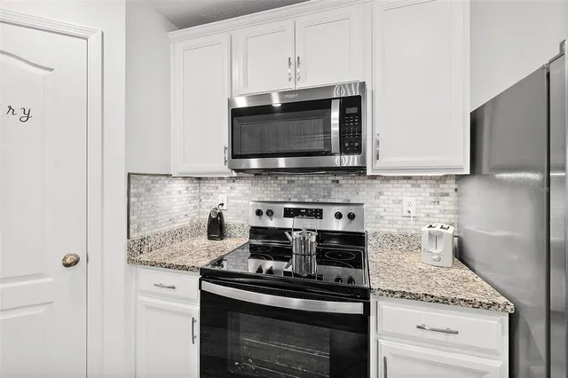 a kitchen with stainless steel appliances granite countertop white cabinets stove a sink and dishwasher