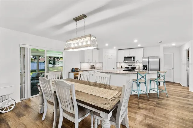 a view of a dining room and livingroom with furniture wooden floor kitchen view