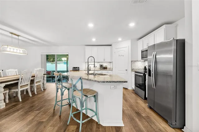 a kitchen with stainless steel appliances granite countertop a table chairs refrigerator and cabinets