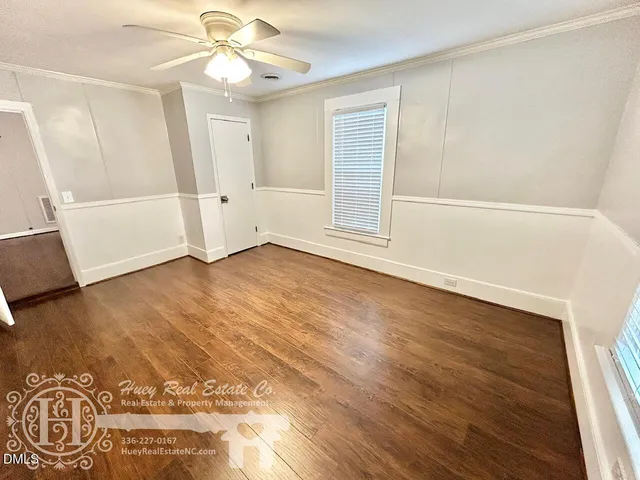 an empty room with wooden floor fan and windows