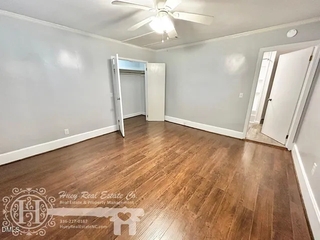 an empty room with wooden floor and fan
