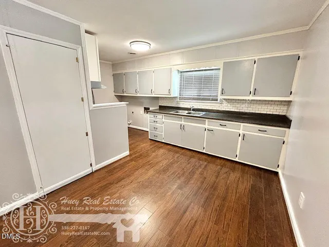 a large white kitchen with sink and refrigerator