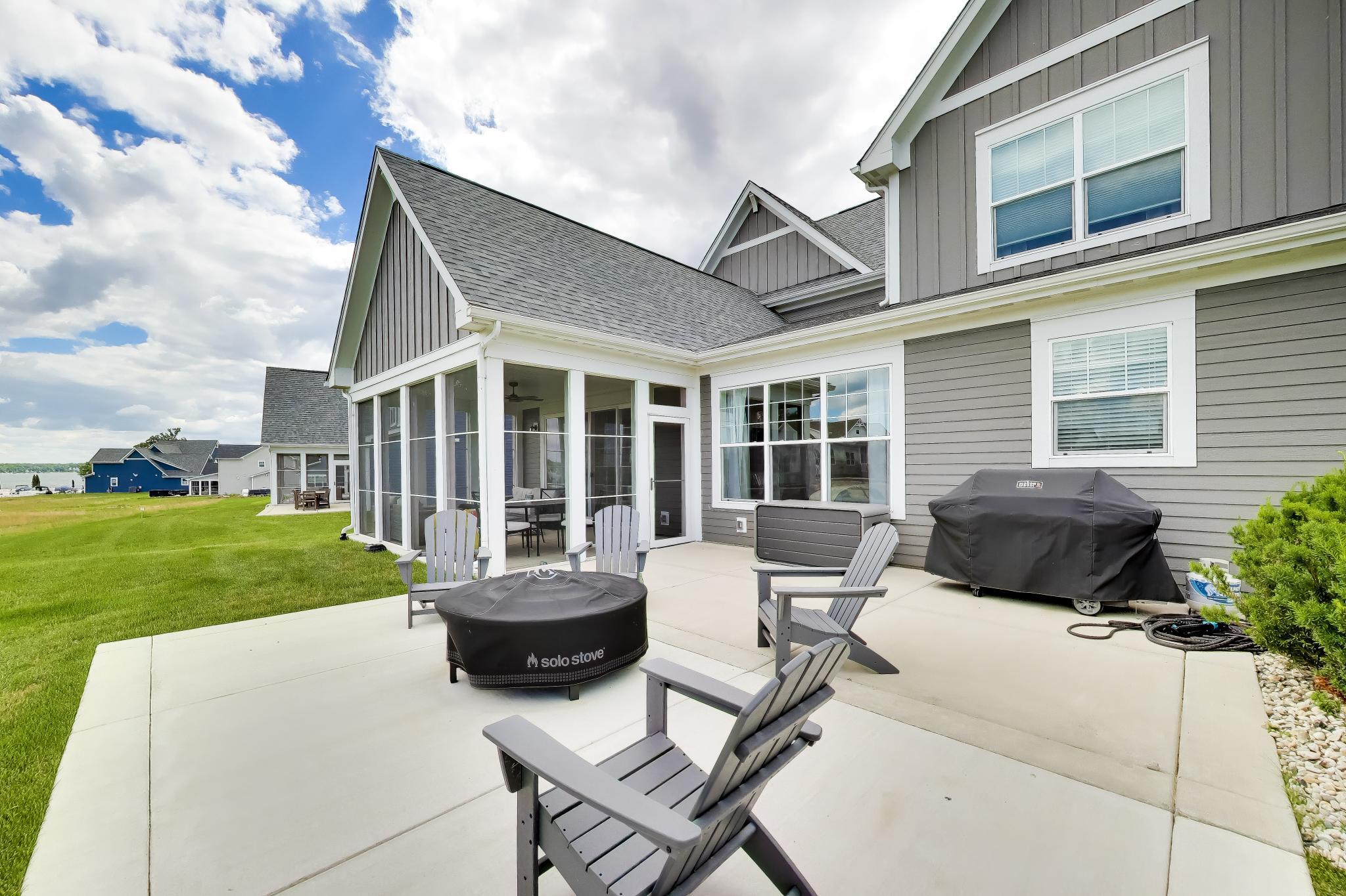 2730 Harbor Court Delavan, WI 53115 - Photo 39 of 47 Rear patio with screened sunroom access, outdoor seating area, lake-facing lawn, and Delavan Lake views beyond.