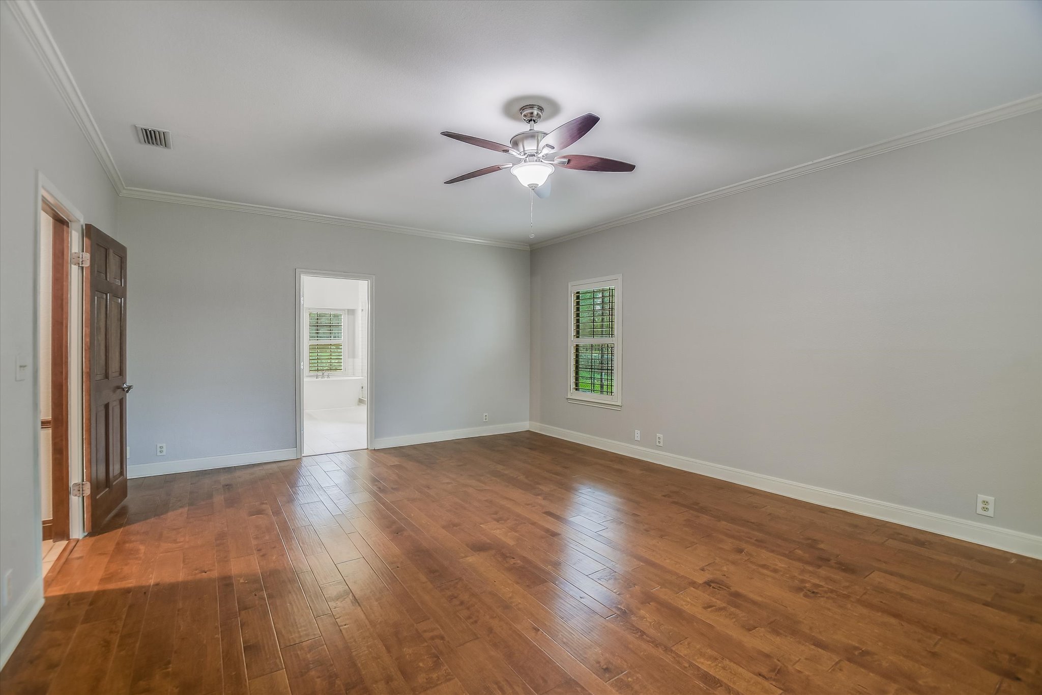 328 Fawnridge Street Georgetown, TX 78628 - Photo 14 of 33 Spacious primary bedroom with engineered wood floors, windows with shutters, ceiling fan, and dual walk-in closets.