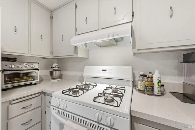 a kitchen with a white stove top oven and cabinets