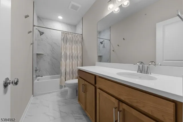a bathroom with a granite countertop sink a toilet and shower