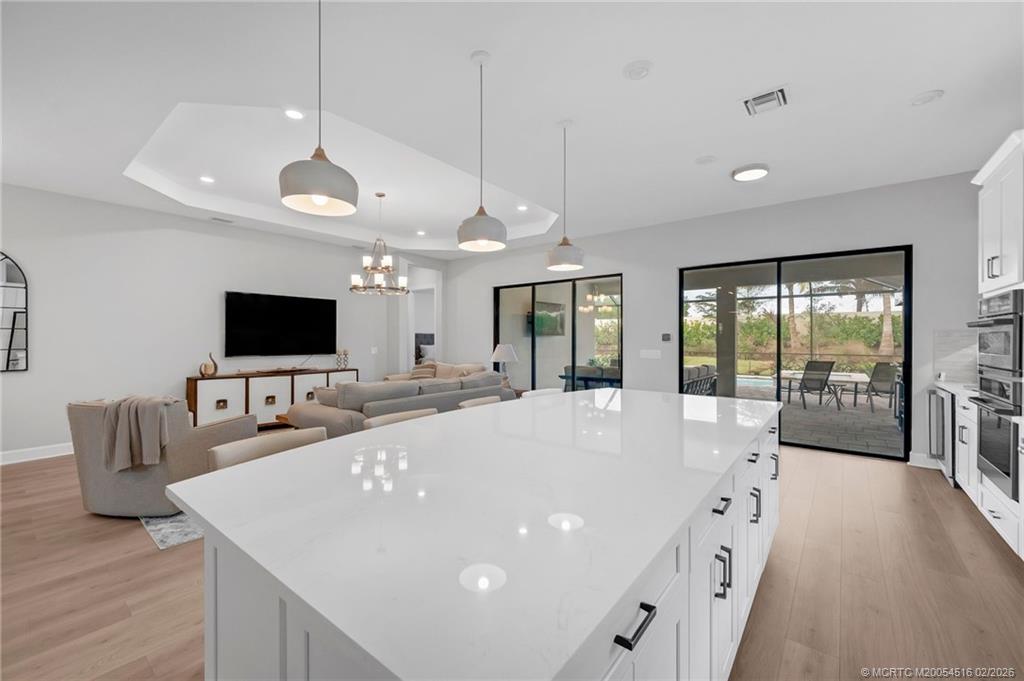 15111 Pescara Street Naples, FL 34114 - Photo 12 of 43 a large white kitchen with a large island in the center windows and a chandelier
