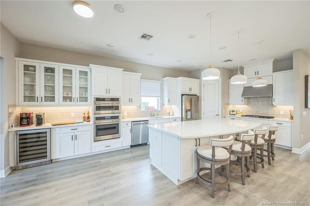 15111 Pescara Street Naples, FL 34114 - Photo 10 of 43 a kitchen with white cabinets and stainless steel appliances
