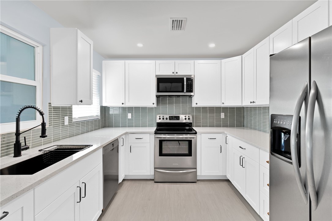 669 Vocelle Avenue Sebastian, FL 32958 - Photo 8 of 34 a kitchen with white cabinets and stainless steel appliances