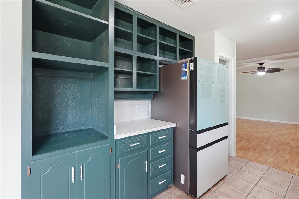 837 Springdale Road Bedford, TX 76021 - Photo 9 of 28 Built-in cabinetry in a deep teal finish, featuring open shelving, enclosed storage, and a white countertop