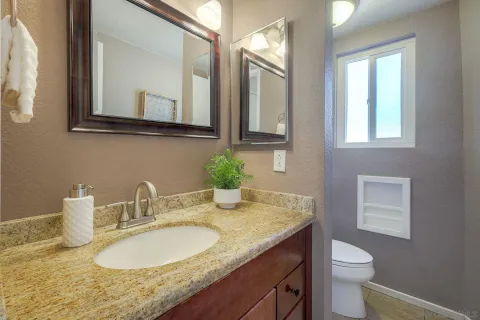 a bathroom with a granite countertop toilet sink and mirror