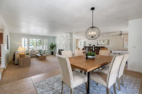 a view of a dining room and livingroom furniture wooden floor a rug and a chandelier