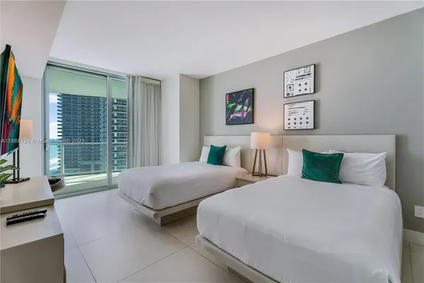 a bedroom with two beds and a large window