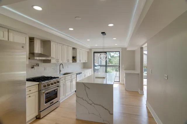 a kitchen with stainless steel appliances kitchen island granite countertop a stove a sink and a refrigerator