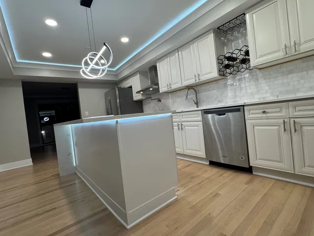a view of a kitchen with stainless steel appliances granite countertop wooden cabinets and a wooden floor