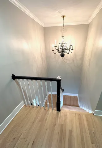 a view of a room with a hanging light and hardwood floor