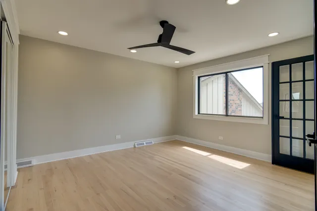 a view of empty room with wooden floor and fan
