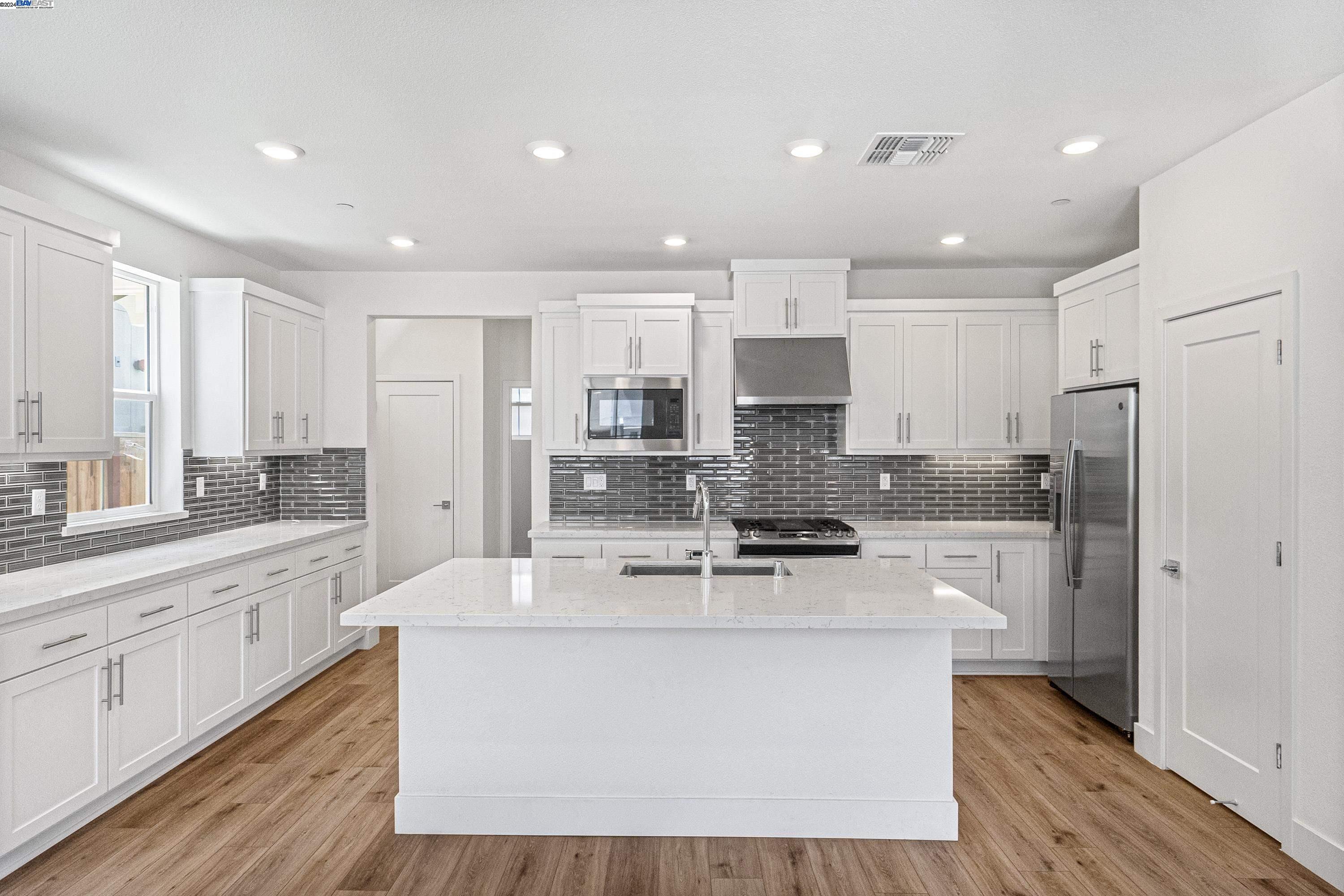 9657 Pontoon Way Newark, CA 94560 - Photo 5 of 46 a large kitchen with stainless steel appliances a large counter top a stove a refrigerator and white cabinets