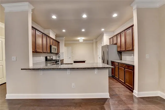 a large kitchen with stainless steel appliances granite countertop a sink a stove and a refrigerator