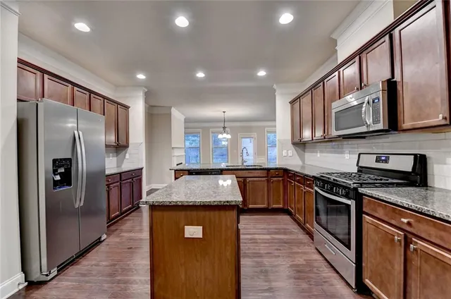 a kitchen with stainless steel appliances granite countertop a refrigerator a stove top oven and a sink