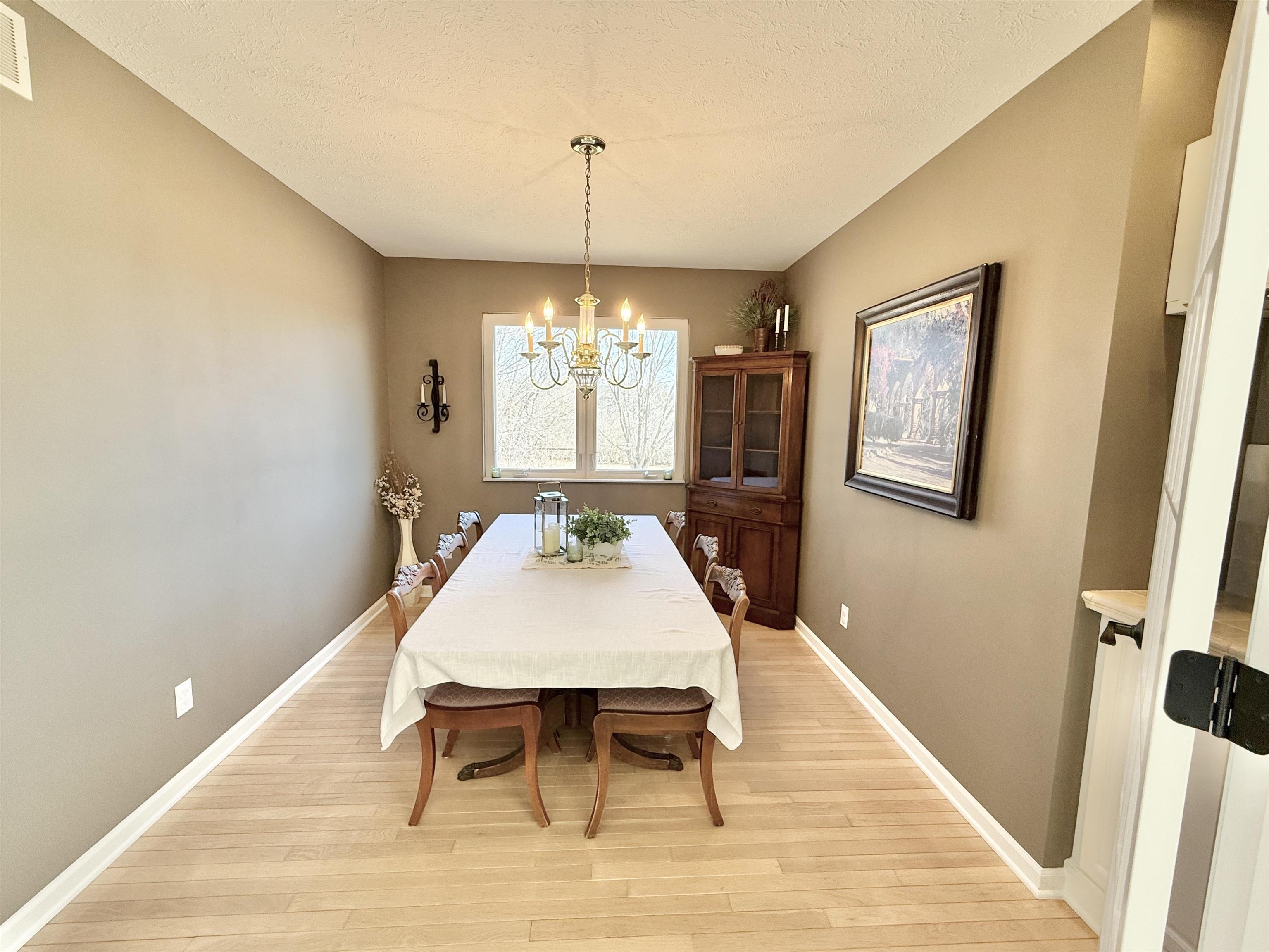 7188 Edwardsville Road Rockford, IL 61102 - Photo 25 of 73 a dining room with wooden floor a chandelier a wooden table and chairs