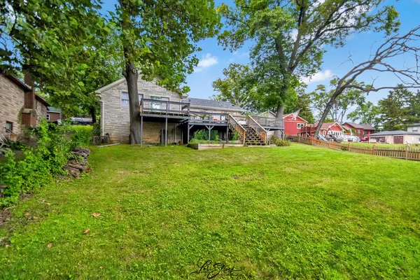 a house that is sitting in the grass with tress in the background
