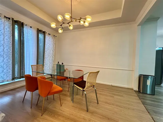 a dining room with wooden floor a chandelier a glass table and chairs