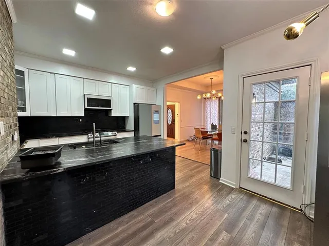a kitchen with kitchen island granite countertop a sink cabinets and wooden floor