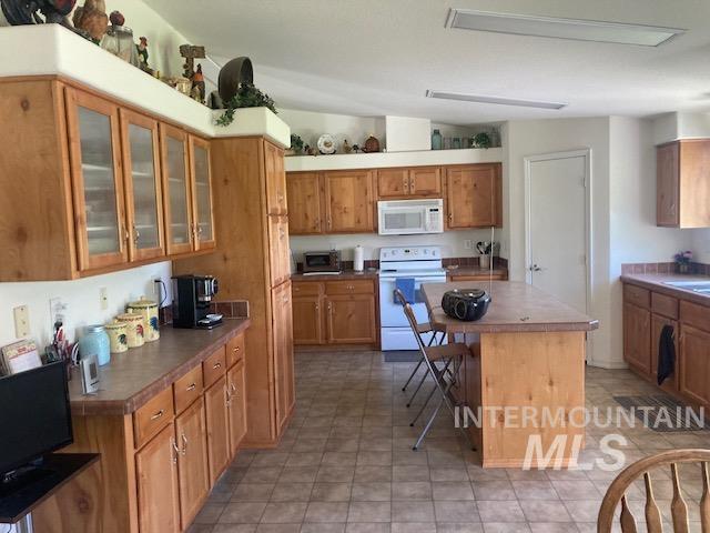 1095 County Road 70 Weiser, ID 83672 - Photo 9 of 44 Kitchen featuring extensive light wood-finish cabinetry, a central island with seating, patterned tile flooring, and integrated overhead lighting