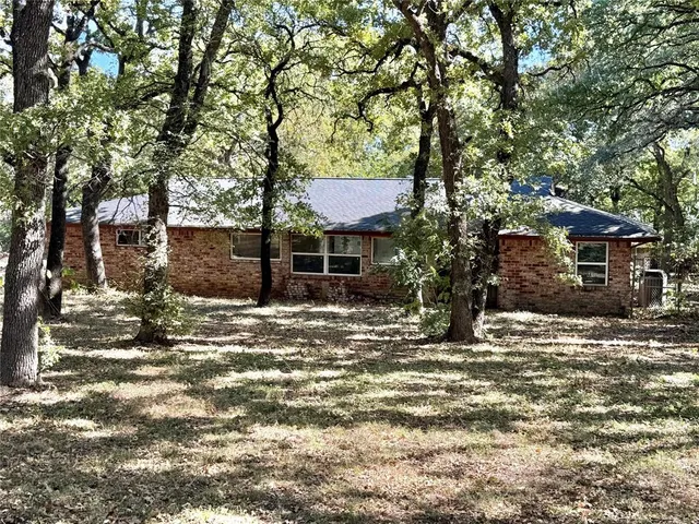 a view of a house with a yard tree and wooden fence