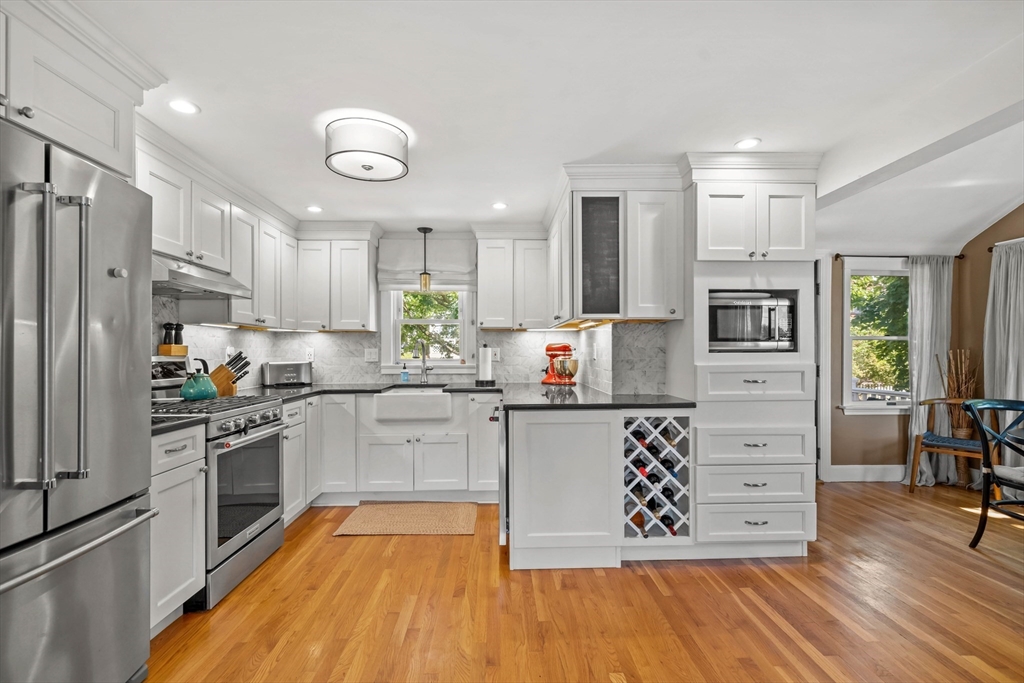 7 Leonard Circle Medford, MA 02155 - Photo 11 of 33 a kitchen with stainless steel appliances granite countertop a refrigerator a stove oven and white cabinets with wooden floors