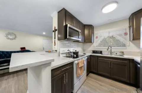 a kitchen with a sink a stove top oven and wooden floor