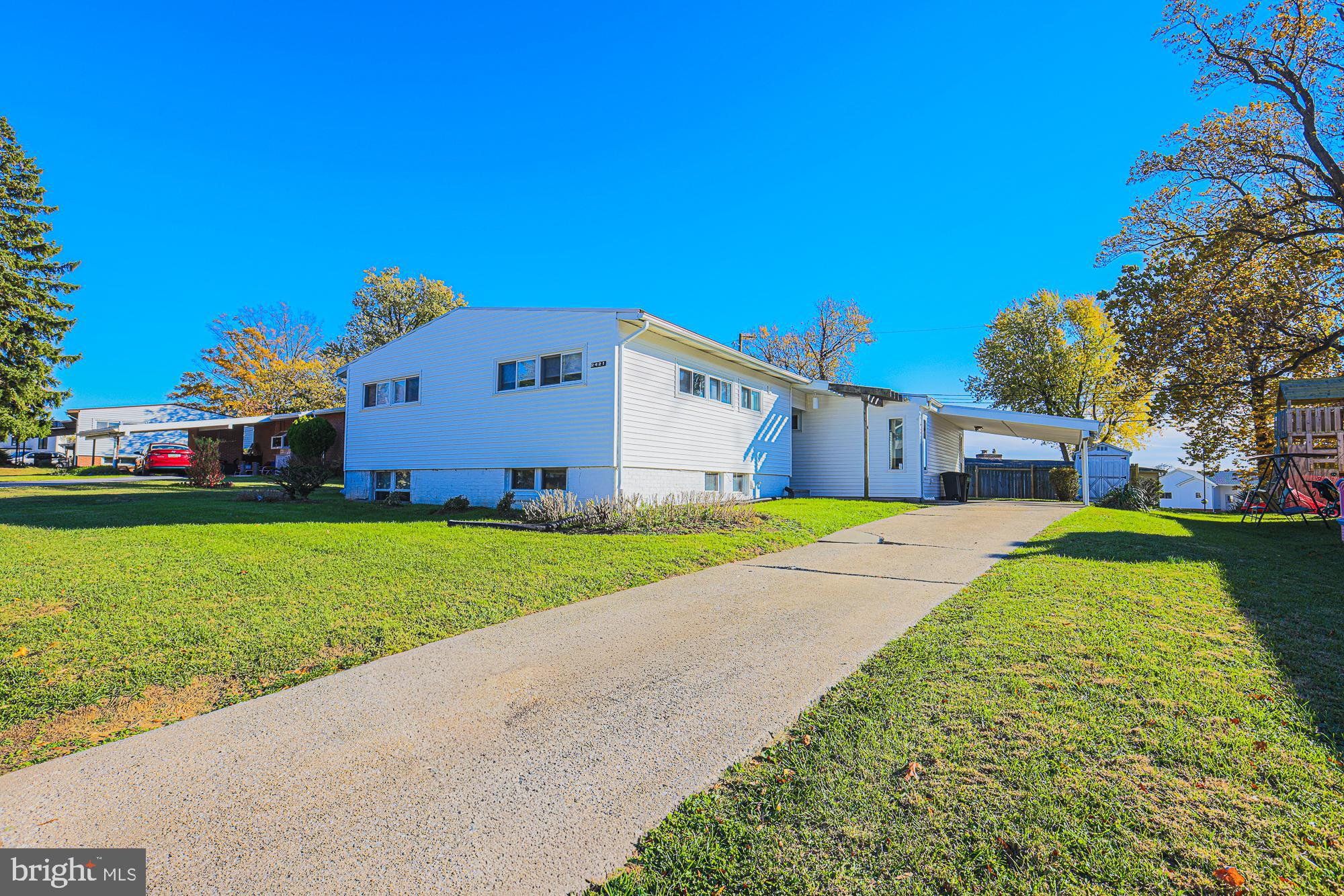 a front view of house with yard and trees in the background