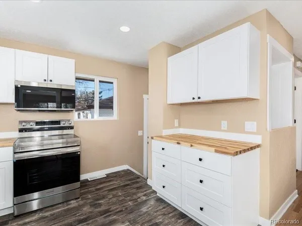 a kitchen with granite countertop white cabinets and stainless steel appliances