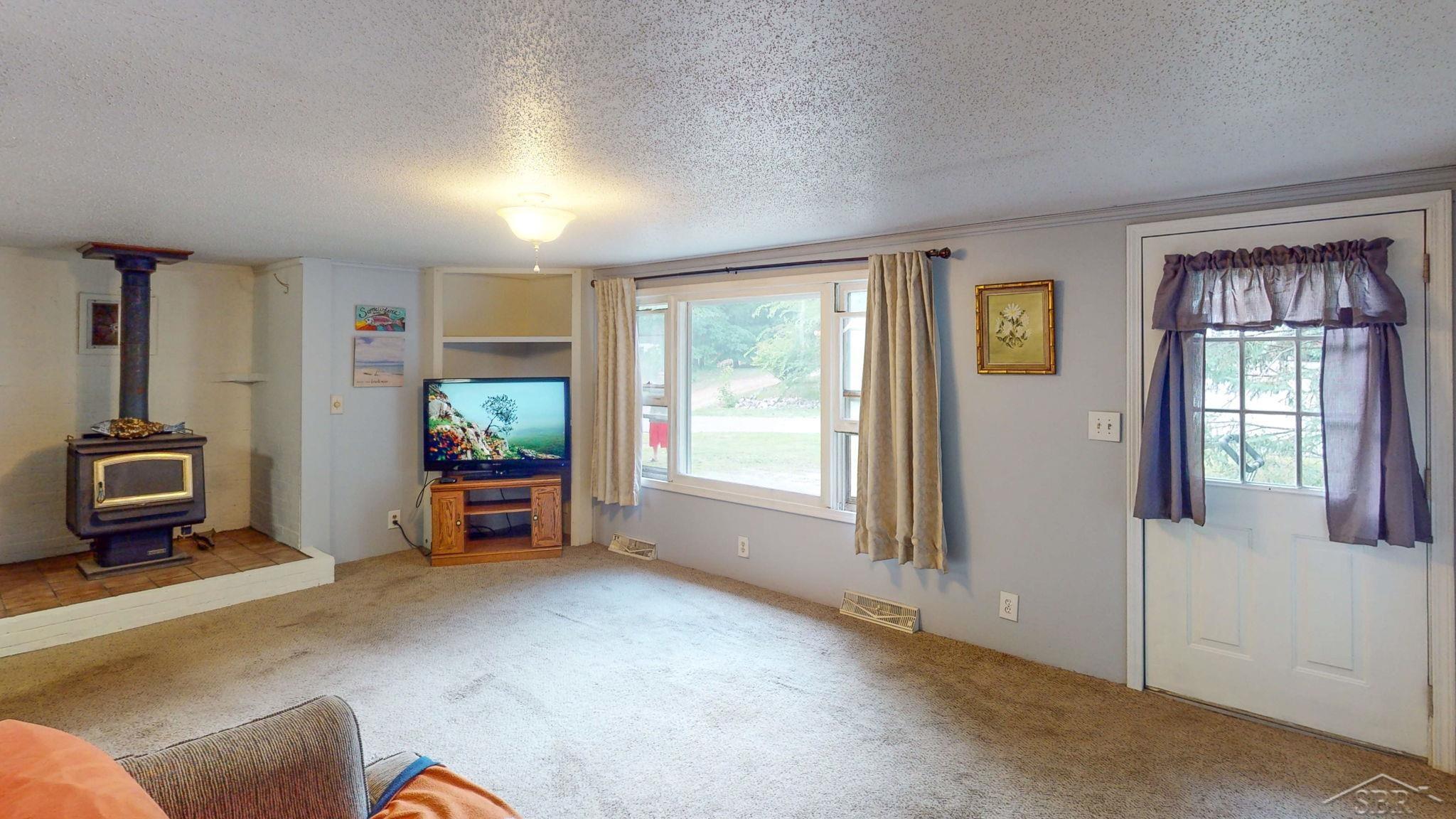 670 Lone Pine Road Harrison, MI 48625 - Photo 14 of 34 This room is larger in person and it's open to the kitchen and front door. If entertaining is your thing, this property has the space for it, inside and out.