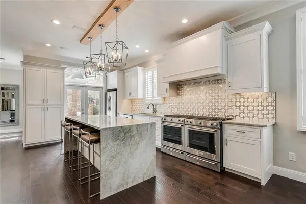 a kitchen with stainless steel appliances a kitchen island hardwood floor and a sink