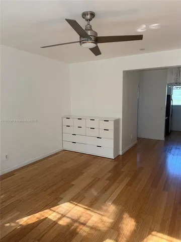 a view of a room with cabinet a ceiling fan and wooden floor