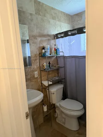a bathroom with a sink a toilet and shower curtain