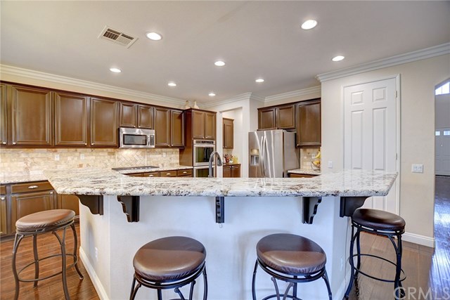8546 Millpond Place Riverside, CA 92508 - Photo 11 of 60 a kitchen with stainless steel appliances granite countertop a stove a sink a refrigerator white cabinets and chairs