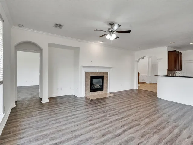 a view of an empty room with wooden floor fireplace and a window