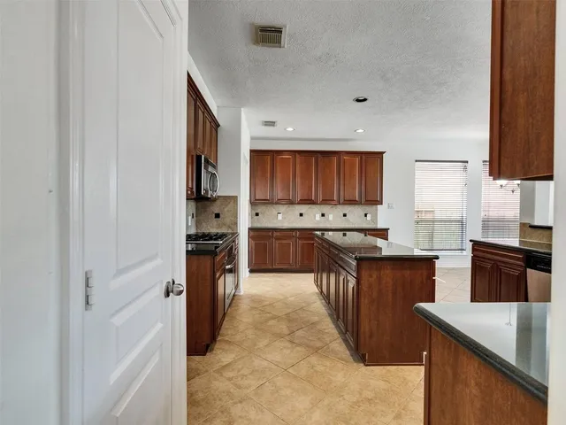 a large kitchen with stainless steel appliances granite countertop a sink counter space cabinets and a refrigerator