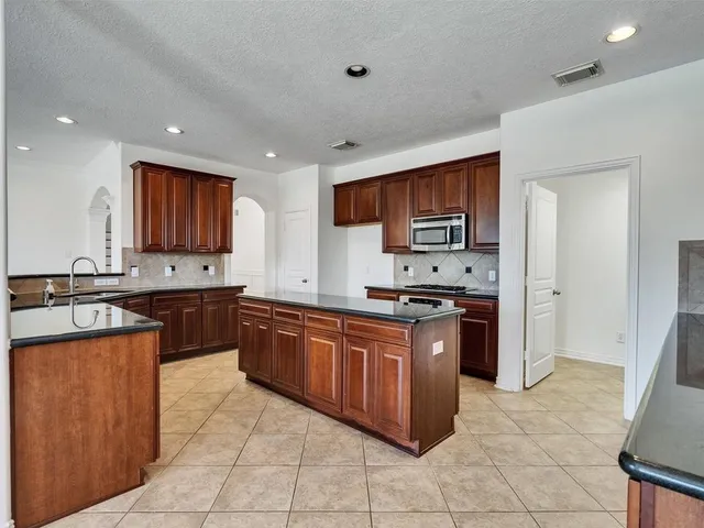 a kitchen with stainless steel appliances granite countertop a stove a sink dishwasher and a refrigerator