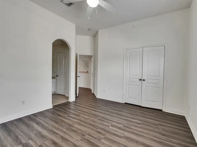 an empty room with wooden floor chandelier fan and windows