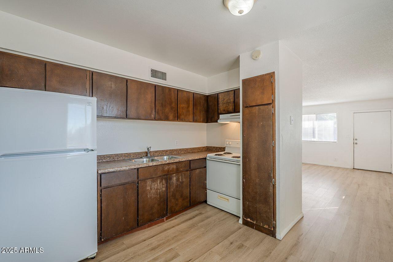 2608 West Ocotillo Road Phoenix, AZ 85017 - Photo 19 of 56 a kitchen with stainless steel appliances granite countertop a refrigerator a sink and white cabinets with wooden floor