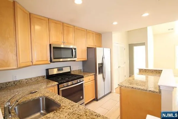 a kitchen with stainless steel appliances granite countertop a stove a sink and a refrigerator