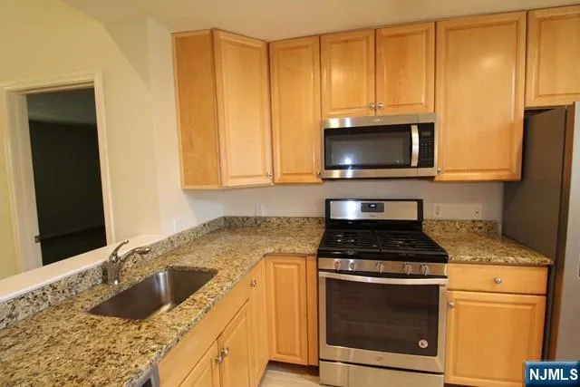 a kitchen with granite countertop cabinets stainless steel appliances and a counter space